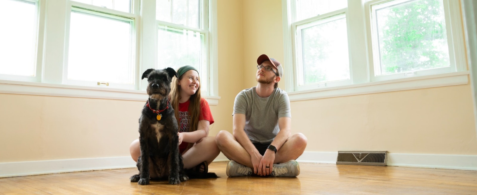 couple with dog sitting on floor of new home