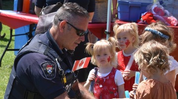 Officer with school kids standing next to a police vehicle