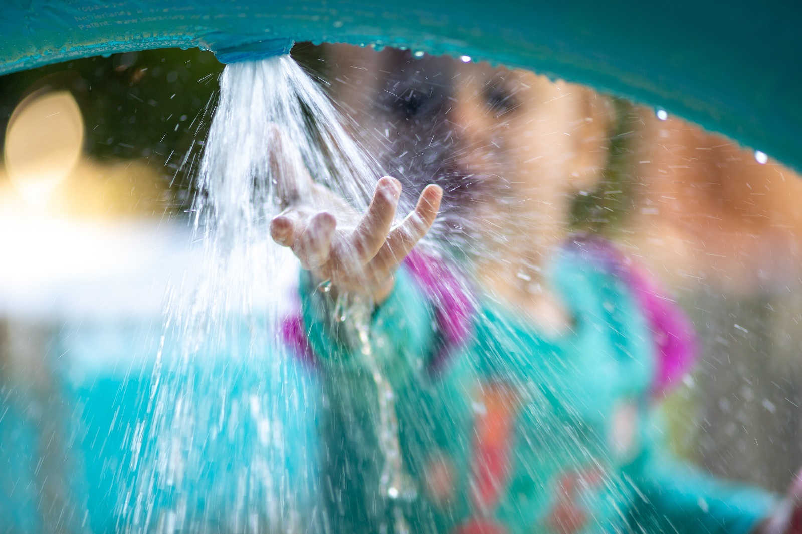 Young children with hand in water spraying from hose